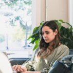 The young adult woman sits on a sofa at the coffee shop