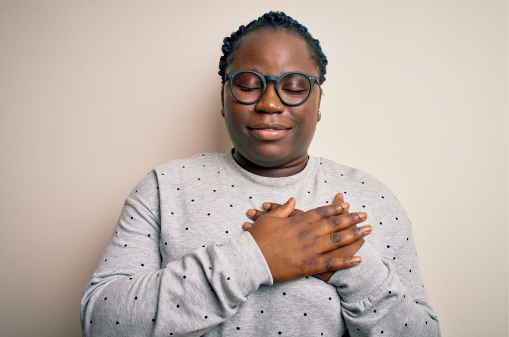 Young woman with hands on heart to soothe anxiety symptoms