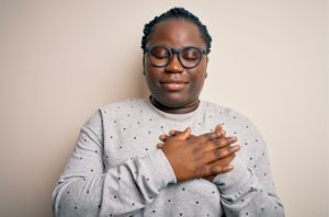 Young woman with hands on heart to soothe anxiety symptoms
