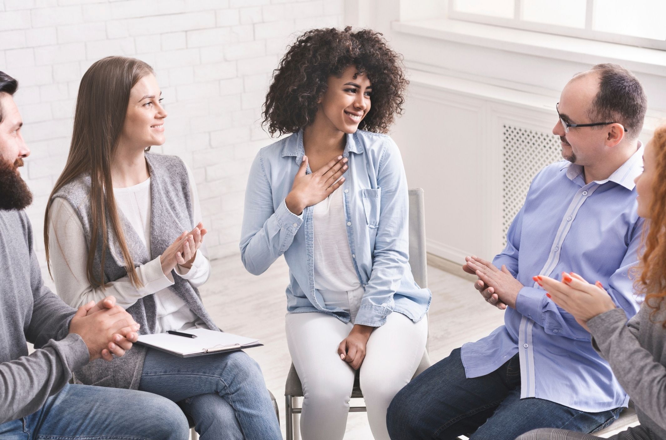 happy woman in addiction recovery group shows what addiction treatment is