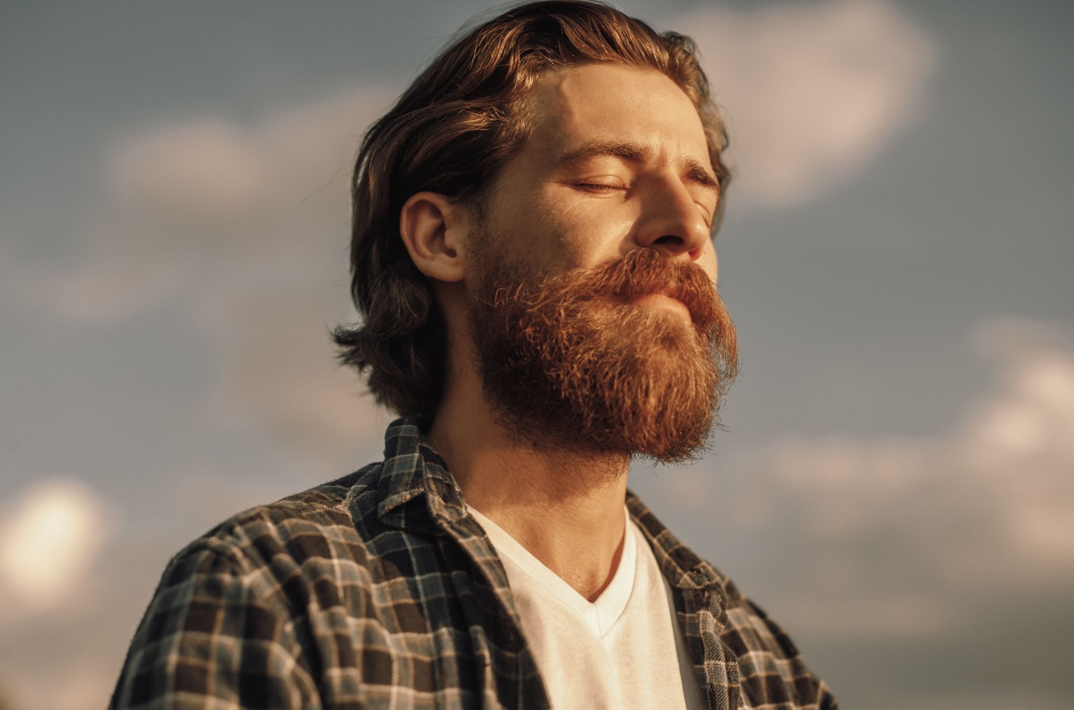 man with beard and eyes closed experiencing anxiety signs and symptoms