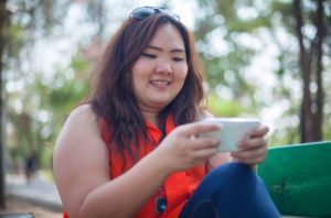 woman in park using social media on phone impacting her mental health
