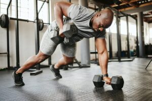 Bald male lifting dumbbells in the gym, illustrating the potential impact of finasteride on testosterone levels.